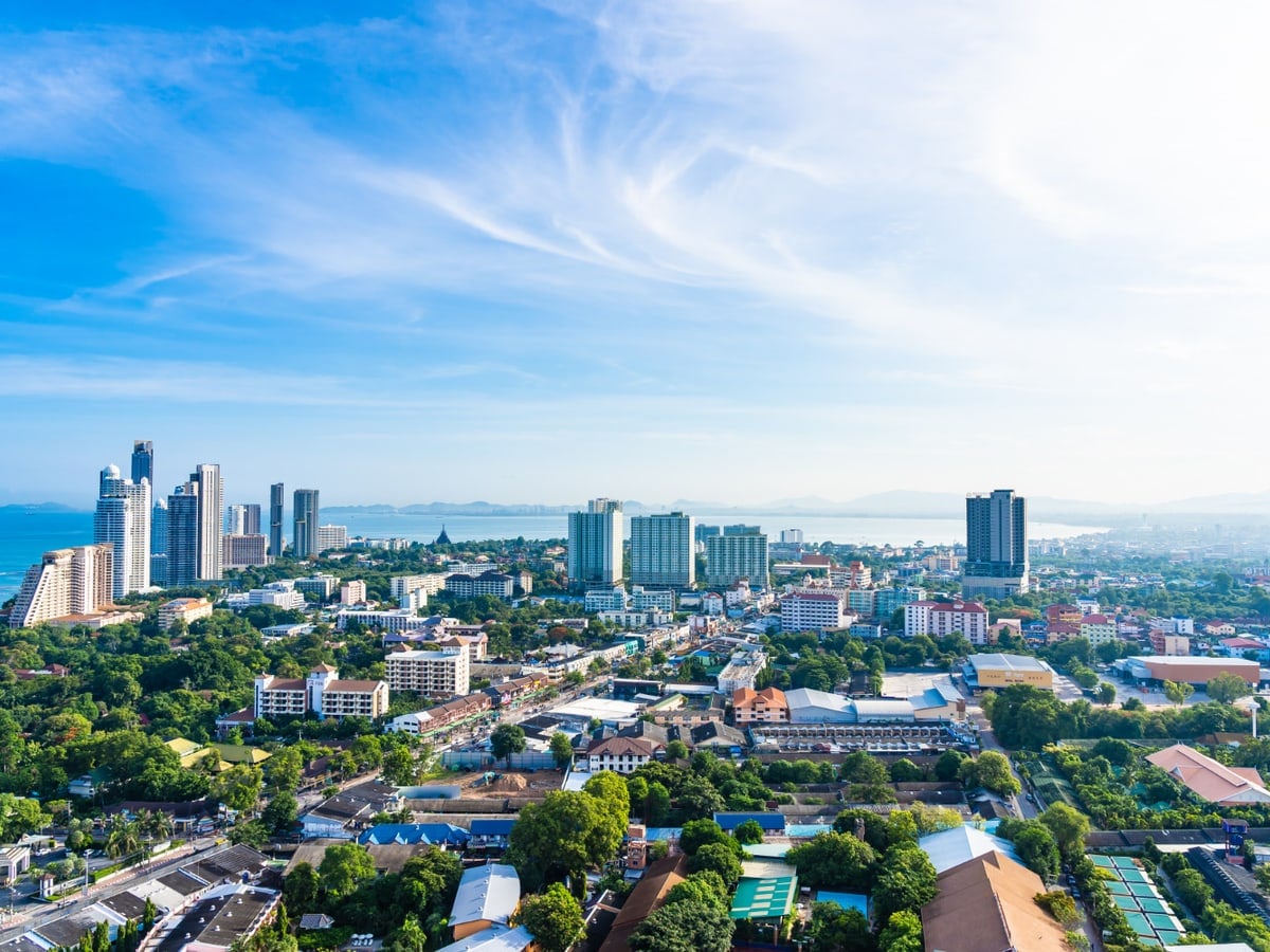 A coastal city in Thailand on a bright day, towers along the sea.