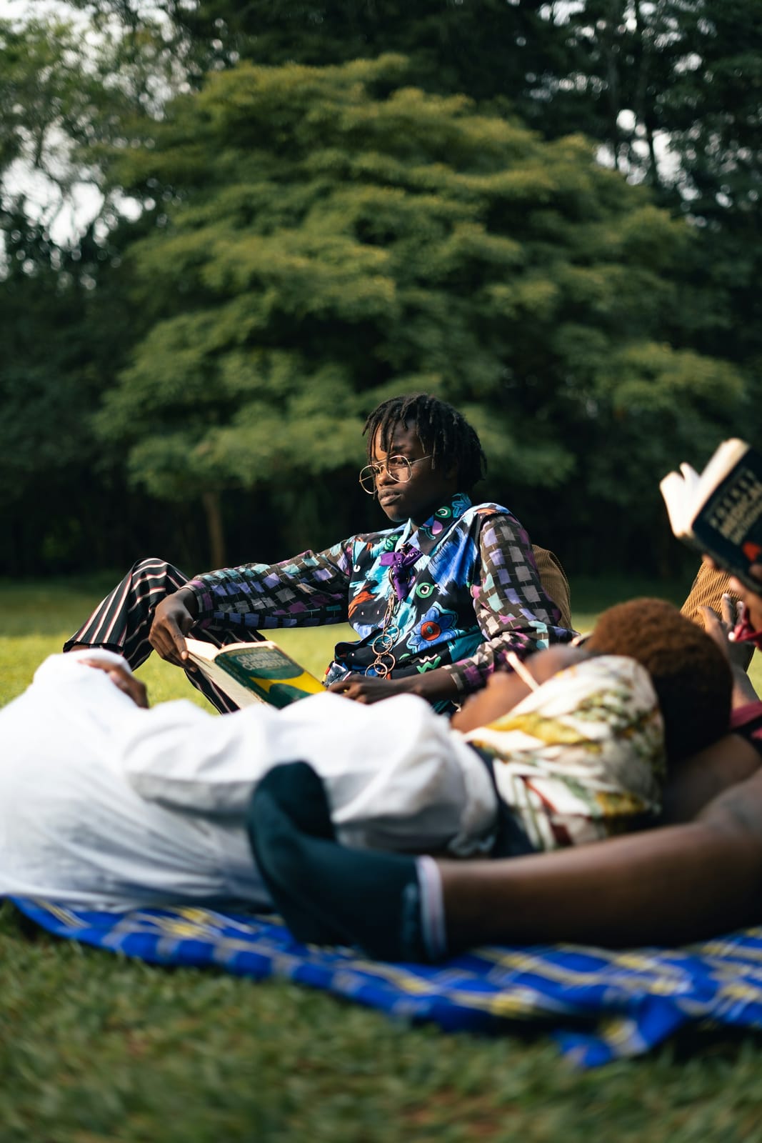Friends lying together on a blue blanket in the park.